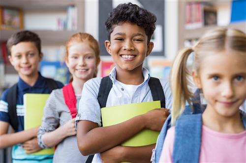 Four students standing in a row holding notebooks 